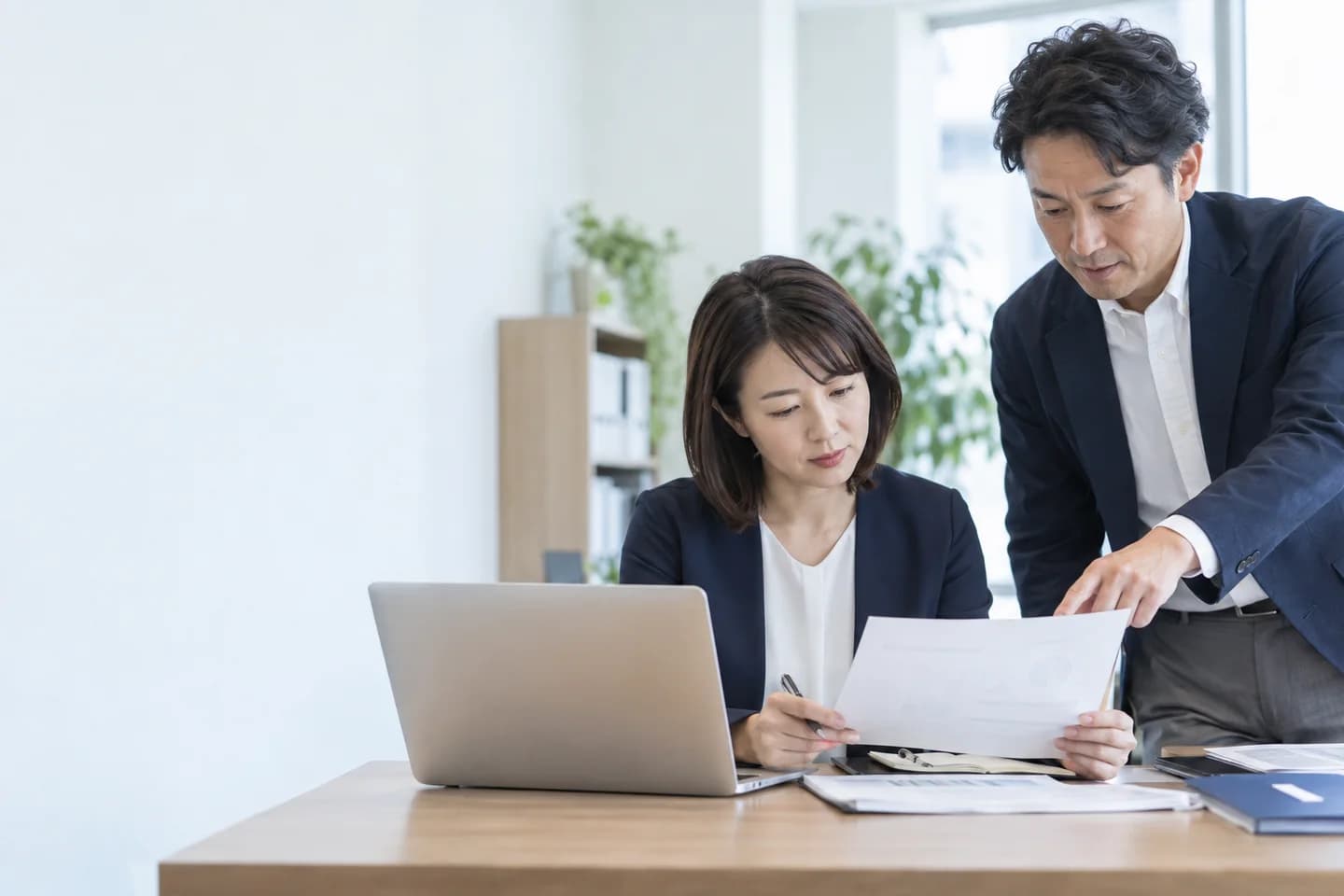 オフィスで申請準備の資料を確認する担当者たち。AI生成の説明用写真。